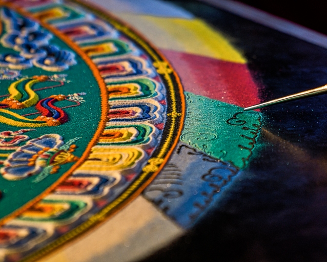 The three outer rings surround the mandala. The outmost ring represents flames of various colors. The black and yellow ring represent a three dimensional cosmic dome that surrounds the mandala. The innermost of the three rings consists of lotus petal designs.